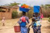 FILE - Women, with children on their backs, carry out chores in Epworth, Zimbabwe, on Nov. 14, 2024. (AP Photo/Aaron Ufumeli, File)