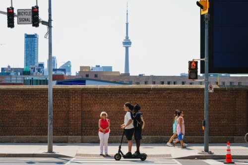 Two kids ride on an electric scooter in Toronto, on Tuesday, Aug. 11, 2026. THE CANADIAN PRESS/Keito Newman