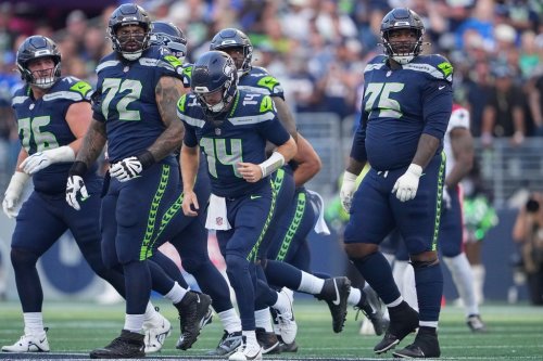 Seattle Seahawks quarterback Sam Darnold (14) is surrounded by guard Grey Zabel (76), tackle Abraham Lucas (72) and guard Anthony Bradford (75) after being sacked during the first half of an NFL football game against the New England Patriots, Wednesday, Sept. 9, 2026, in Seattle. (AP Photo/Lindsey Wasson)