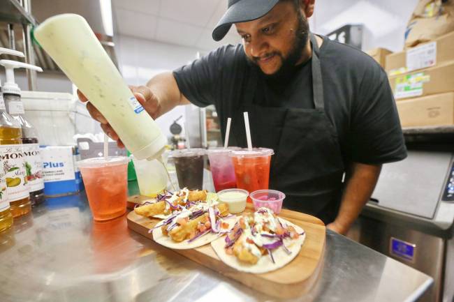 Los Brothers Canteen director of operations Ben Castro adds some avocado crema to a platter of fish tacos on Wednesday afternoon in the canteen kitchen at the City of Brandon Sportsplex. Los Brothers took over the canteen at the Sportsplex this year and held a soft opening earlier this week. The canteen will officially open on Friday morning. (Matt Goerzen/The Brandon Sun)