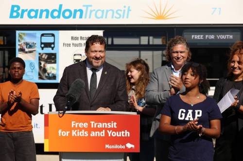 Flanked by students from George Fitton School, Brandon Mayor Jeff Fawcett and school vice-principal Shannon Vogel, Municipal and Northern Relations Minister Glen Simard speaks during an announcement about free public transit for youth in Brandon on Thursday. (Tim Smith/The Brandon Sun)