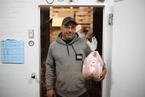 Brian Blanchard with a frozen turkey for sale in front of the freezer at his farm on Friday. Blanchard and his partner, Alicia Dyck, raised 100 turkeys this year for sale. (Tim Smith/The Brandon Sun)