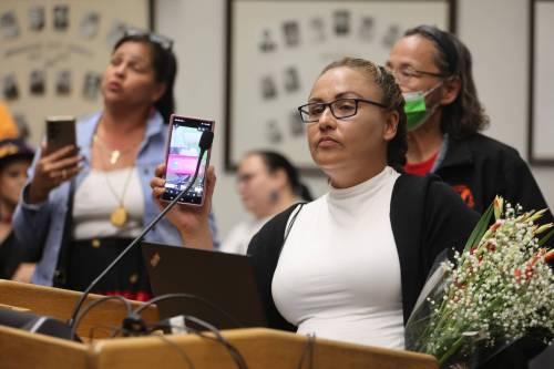 Crystal Delvenne holds up her cellphone to play audio at the end of a Brandon City Council meeting on Monday. (Alex Lambert/The Brandon Sun)