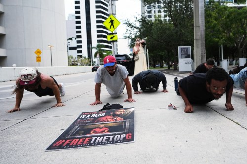 Supporters of Andrew and Tristan Tate do push-ups outside of the C. Clyde Atkins U.S. Courthouse as they fight extradition to the United Kingdom on charges of rape and sex trafficking at a bond hearing, Thursday, Aug. 27, 2026, in Miami. (AP Photo/Lynne Sladky)