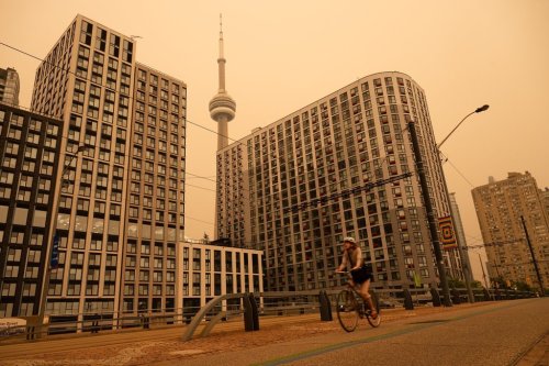 A woman bikes along the waterfront in Toronto as wildfire smoke fills the city, on Wednesday, July 15, 2026. THE CANADIAN PRESS/Laura Proctor
