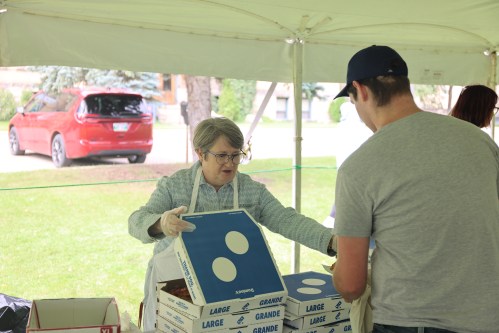 Brandon University Student Services staff member Joan Garbutt gives a new student a slice of pizza during fall orientation on Tuesday afternoon. (Abiola Odutola/The Brandon Sun)