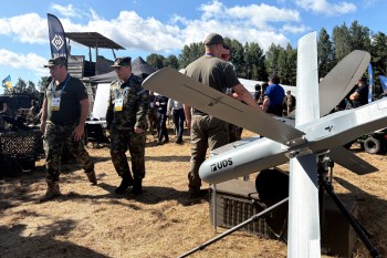 Military personnel walk past a drone made by Unmanned Defense Systems (UDS) during NATO's Baltic Trust exercise on Aug. 13, 2026, in Selijas, southwestern Latvia. THE CANADIAN PRESS/Stéphane Blais