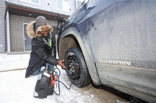 Kola Ositayo checks the tire pressure in his spare tire after changing it following having his tired slashed overnight in the parking lot of The Groves along Tracey Street in Brandon&rsquo;s south end on March 11. A total of 83 vehicles in Brandon&rsquo;s south end were damaged during the spree. (Tim Smith/The Brandon Sun files)