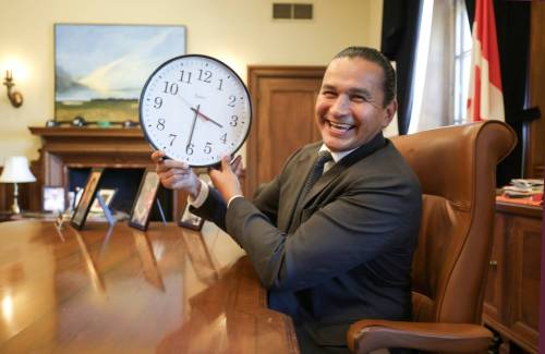 Premier Wab Kinew poses for a photo with a clock in his hands at the Legislative Building in September after declaring Manitoba will permanently adopt daylight saving time. (Ruth Bonneville/Winnipeg Free Press)