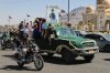 People ride in a pickup truck during a funeral procession for a Houthi officer in Sanaa, Yemen, Saturday, Oct. 17, 2026. The Arabic banner reads, 