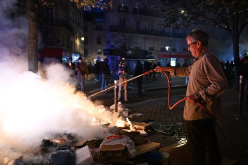A man tries to extinguish a fire during clashes between protesters and police in Paris, Sunday, Oct. 18, 2026. (AP Photo/Emma Da Silva)