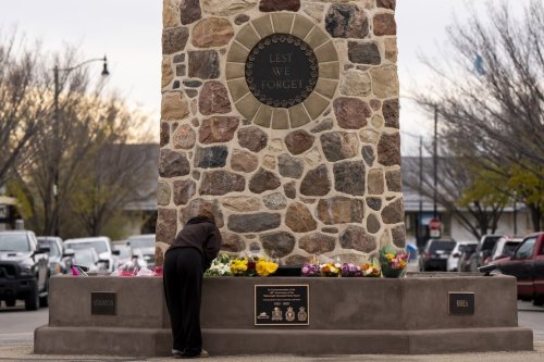 A young woman pays respects to the victims of a fire that killed four soldiers at CFB Wainwright, at the Memorial Clock Tower on Main Street, in Wainwright, Alta., on Monday, Oct. 19, 2026. THE CANADIAN PRESS/Christopher Katsarov